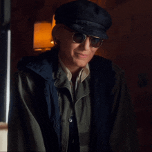 a man wearing a hat and sunglasses is smiling and looking at the camera