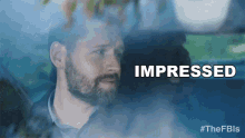 a man with a beard is sitting in a car and the word impressed is above him