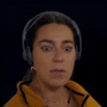 a woman is wearing headphones and a yellow jacket .