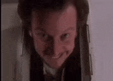 a man in a suit and tie is smiling while looking out of a hole in the wall .