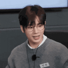 a young man wearing glasses and a name tag that says ' 인턴 ' on it