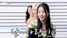 a girl in a green and white striped sweater stands in front of a striped wall with the number fifty fifty written on it
