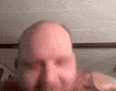 a close up of a bald man 's face with a beard .