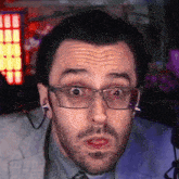 a close up of a man wearing glasses making a surprised face