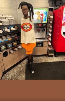 a man standing in front of a soda machine wearing a t-shirt that says ultimate