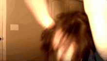 a woman is standing in front of a door with her hair in a messy bun .