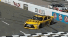 a yellow race car is driving down a race track and crossing the finish line .