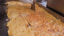 a person is cutting a large omelet with a spatula and the words made in animatica are visible in the corner