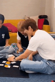 a group of young men are sitting on the floor playing a board game .