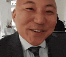 a bald man wearing a suit and tie is smiling