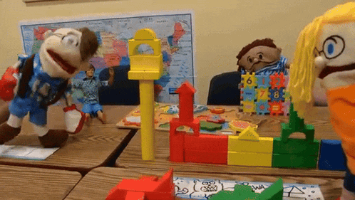a group of puppets are playing with blocks and a map in the background