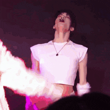 a woman wearing a white crop top and a necklace