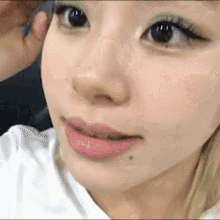 a close up of a woman 's face with a white shirt on .
