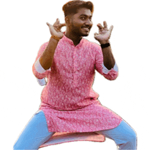 a young man wearing a pink shirt and blue pants is making a funny face