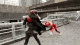 a man in a red and black superhero costume is fighting another man in a black suit