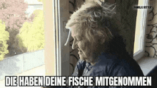 an elderly woman is sitting in front of a window and looking out the window .