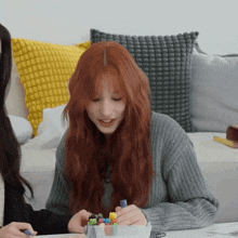 a girl with red hair is sitting at a table with markers
