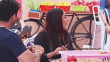 a man and a woman are sitting at a table with a basket of fruit in the foreground