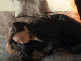 a woman in a black jacket is laying on the floor
