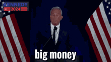 a man in a suit and tie is giving a speech in front of an american flag and the words big money