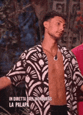 a shirtless man in a black and white shirt is standing in a jungle .