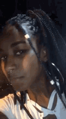 a woman with braids and hoop earrings is taking a selfie .