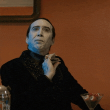a man with white paint on his face holds a martini glass