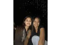 two women are posing for a picture in front of a dark sky