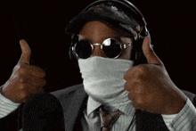 a man wearing a mask and sunglasses is giving two thumbs up
