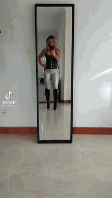a woman taking a picture of herself in front of a mirror with tiktok written on the bottom