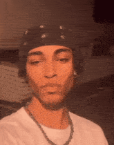 a young man wearing a bandana and a necklace .