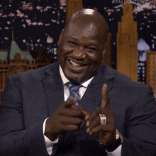 a man in a suit is smiling and pointing at the camera