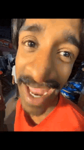 a close up of a man 's face with a mustache and a red shirt .