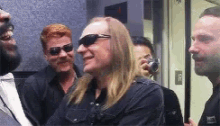 a man with long blonde hair wearing sunglasses is smiling in a group of people