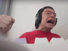 a man wearing headphones and a red shirt with his mouth open