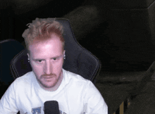 a man with red hair and a beard wearing a white shirt with the letter l on it