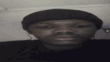 a man wearing a black hat looks at the camera with his eyes closed