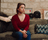 a woman sits on a couch with her hands folded