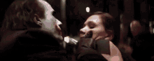 the joker is holding a knife to a woman 's mouth in a dark room .