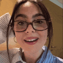 a close up of a woman wearing glasses and a blue shirt