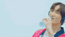a man wearing headphones and a pink sequined jacket is singing into a microphone