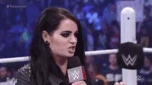 a woman is holding a microphone in a wrestling ring and talking into it .