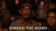 a man with glasses and a bandana on his head is sitting in front of a group of people .
