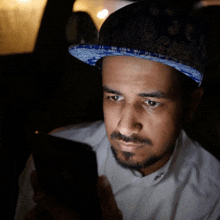 a man wearing a blue hat is looking at his cell phone