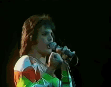 a man is singing into a microphone with his mouth open .
