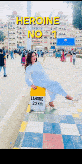 a woman sitting on a yellow block that says lahore 22 km