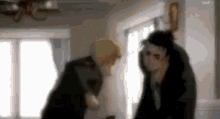 a blurry picture of two men standing next to each other in a room .