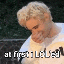 a man with blonde hair is covering his mouth with his hand and the words at first i lol 'ed