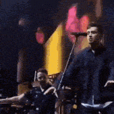 a man singing into a microphone while playing drums