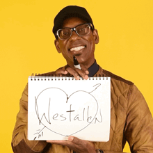 a man holding a notebook that says westalks